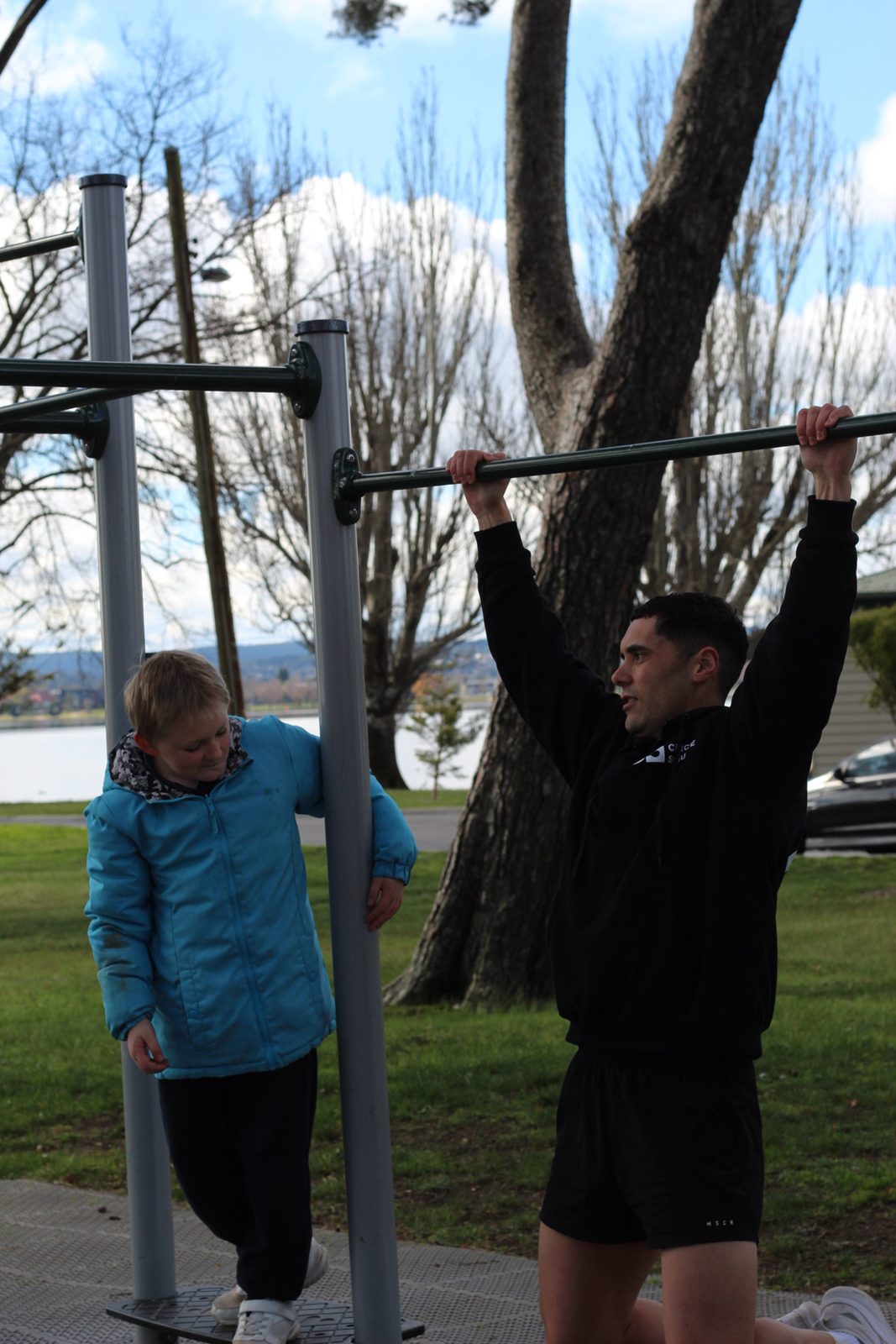 A participant working the pull-up bar with their coach